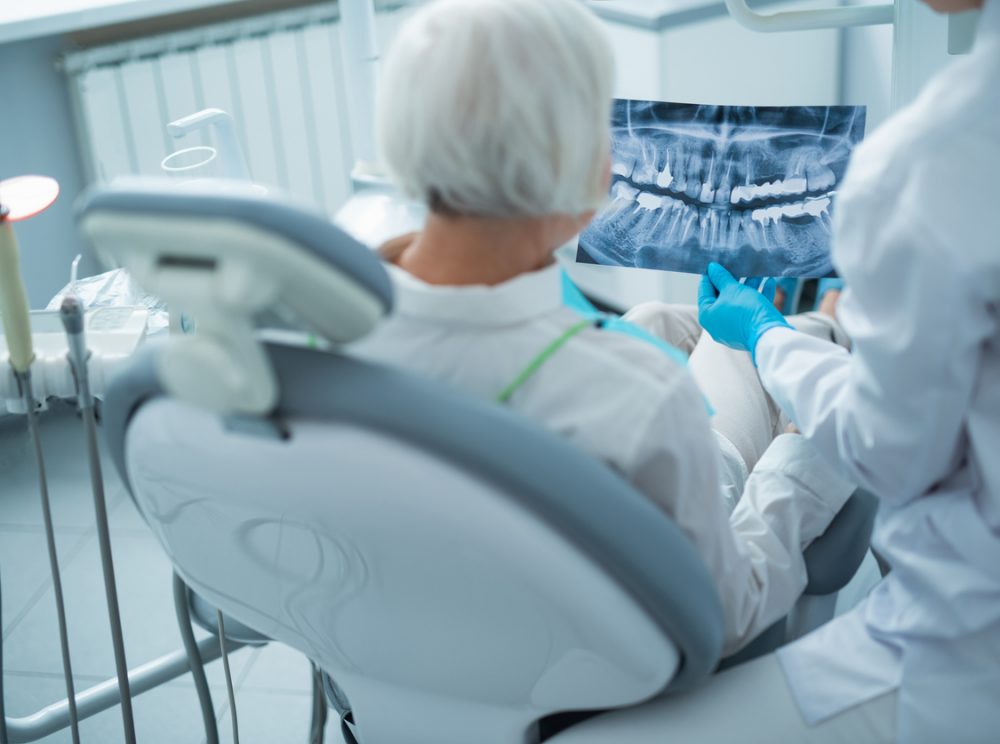 Dentist analysing x-ray with patient in adental office stock photo